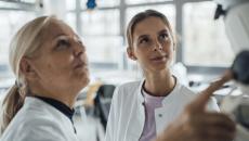 Two people in lab coats work with monitor