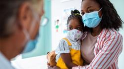 Parent and child in mask talking to doctor in mask