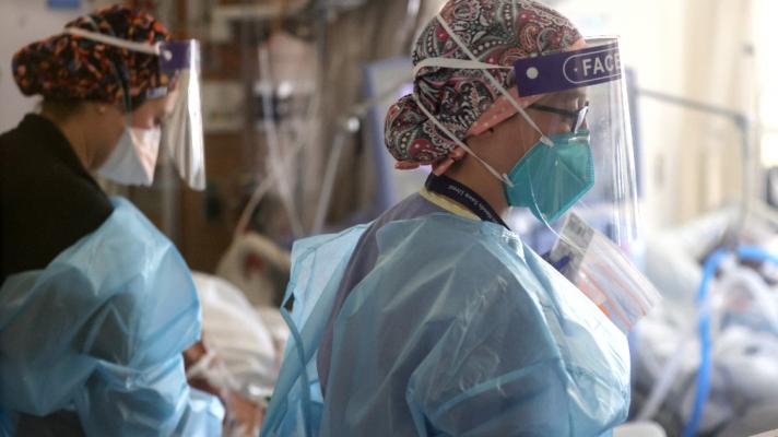 Clinicians wearing personal protective equipment treat patients at a hospital