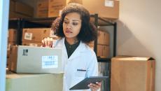 A pharmacist using a digital tablet while doing inventory in the pharmacy stockroom