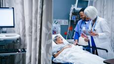 Healthcare workers talking to patient in hospital bed