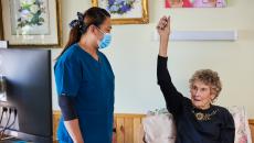 An iAgeHealth nurse assisting a senior patient at home with their virtual checkup