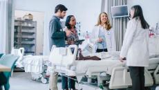 group of healthcare workers talking over hospital bed