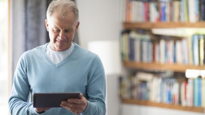 A person in a light blue sweater looking at a tablet