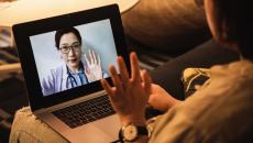 Person waving to doctor on laptop screen