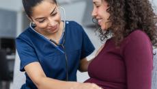 Doctor examining pregnant person with stethoscope