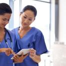 Two nurses checking a patient's medical record on a digital tablet